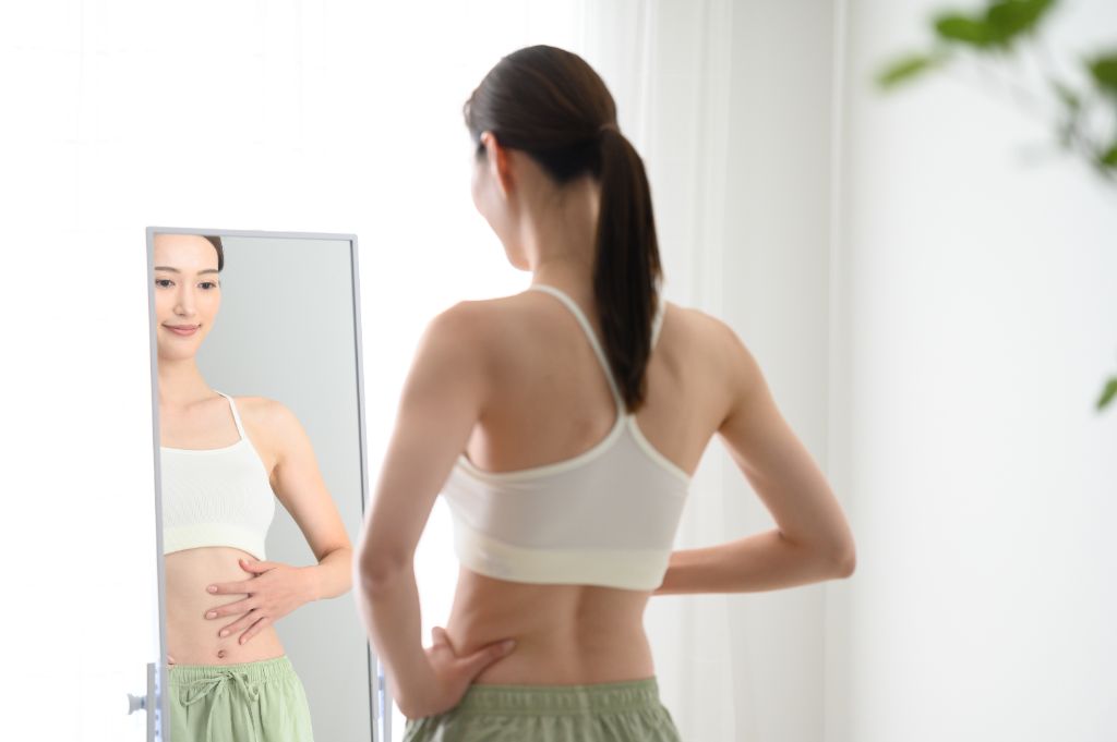 体の変化を確認する女性 - 姿勢改善で体が変わる